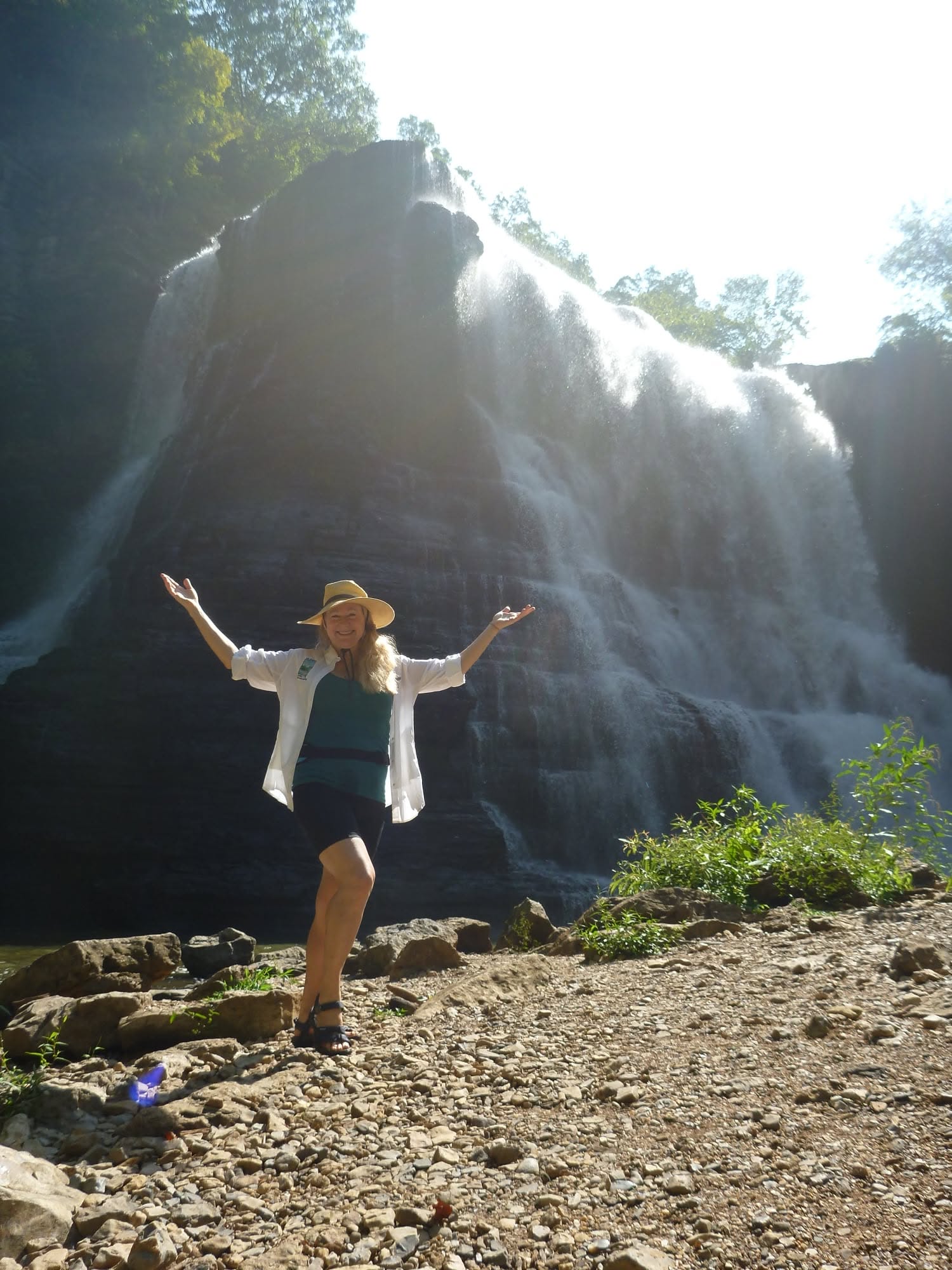 Dr. Tara Perry at a waterfall, arms raised in stillness